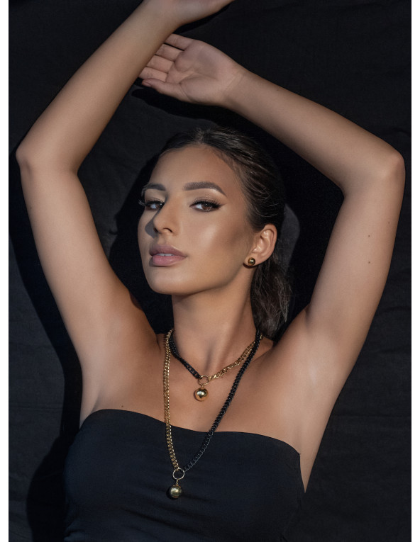 Długi, regulowany naszyjnik z kulą z pozłacanej stali szlachetnej w złotym i czarnym matowym odcieniu.